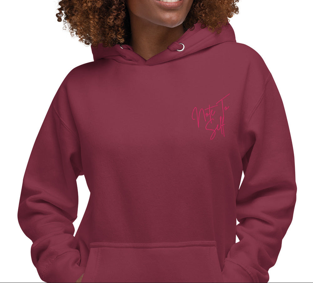 Person wearing a maroon hoodie with pink text that reads Note to Self on the left chest on a white background
