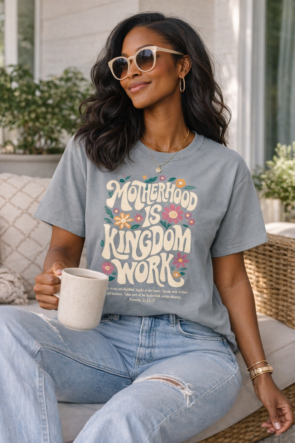 Black woman wearing gray “Motherhood Is Kingdom Work” graphic t-shirt, styled with light wash jeans and gold jewelry, casual everyday outfit for moms, faith-based Christian apparel, stylish modest outfit idea
